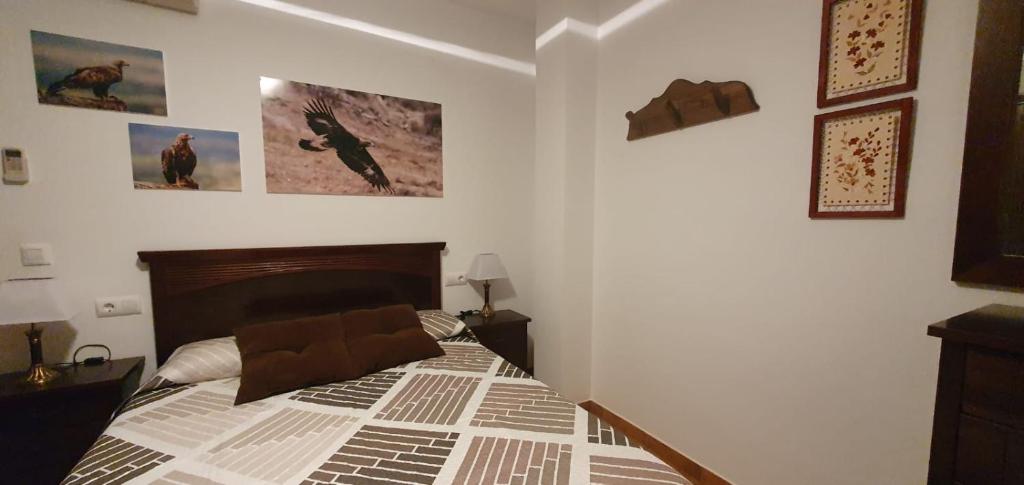 um quarto com uma cama e cartazes na parede em Águila Real em Arroyo Frío