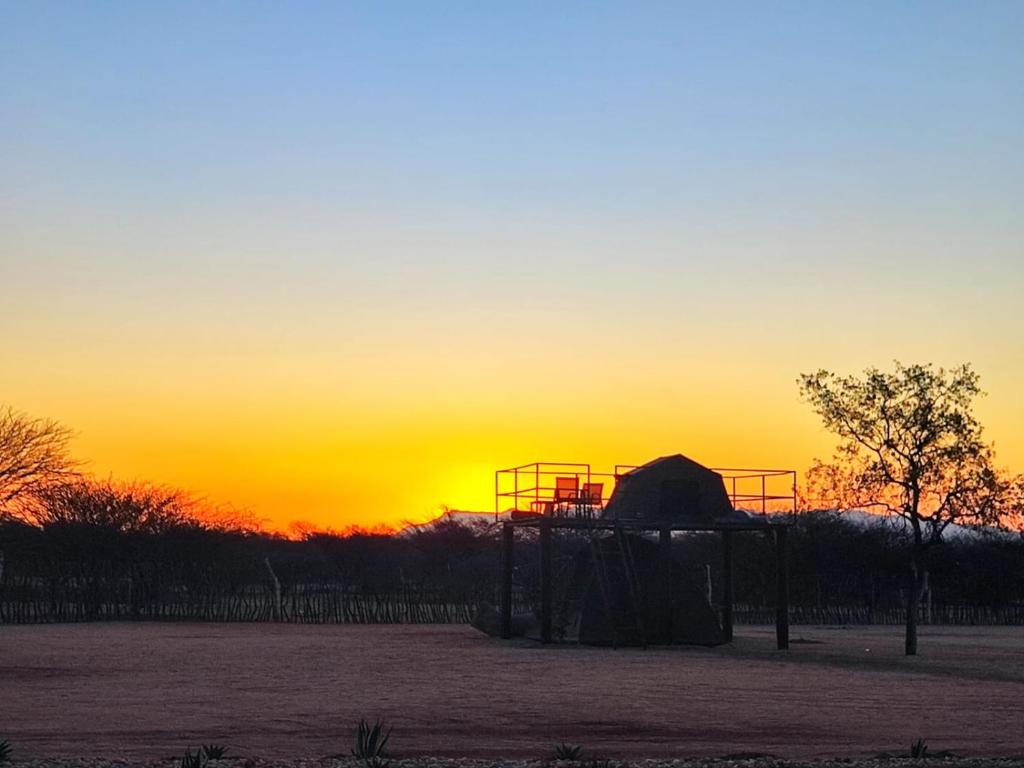 a playground with the sunset in the background at Etoko Farm Camp in Uis