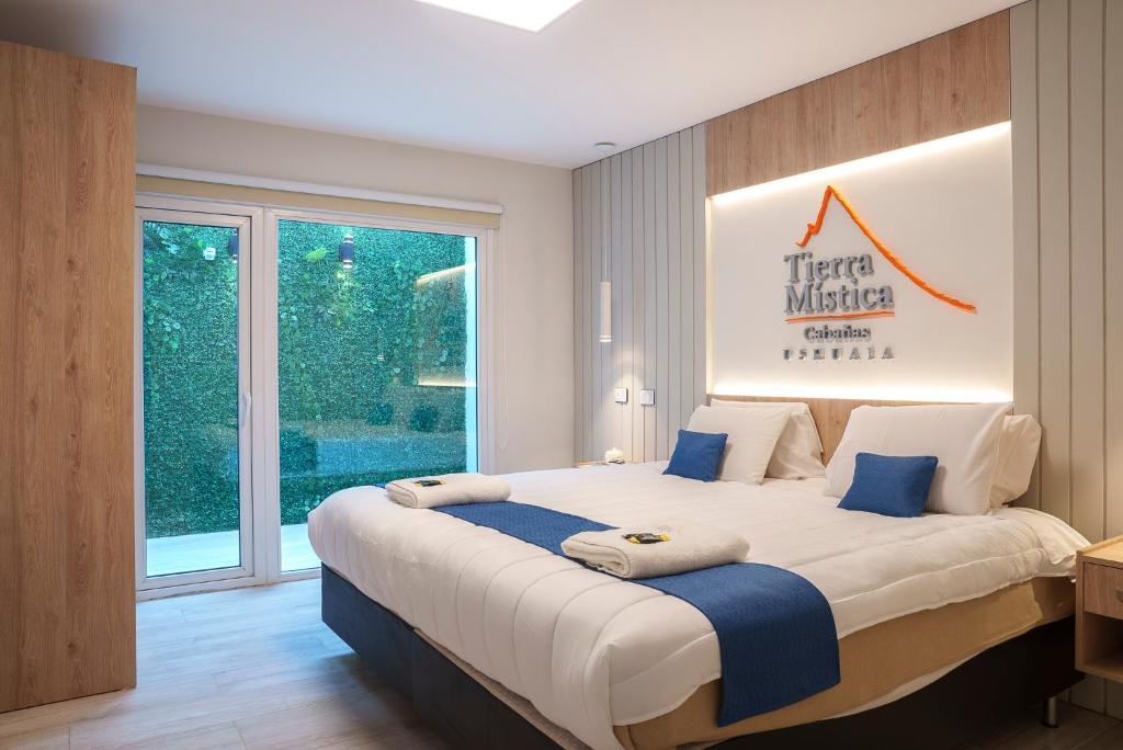 um quarto com uma grande cama branca com almofadas azuis em Cabañas Tierra Mistica em Ushuaia