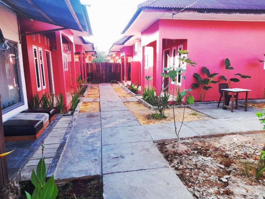 une passerelle entre deux maisons roses avec une table dans l'établissement Baronda Guest House, à Sorong