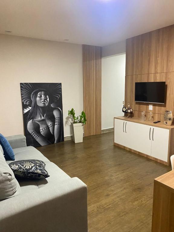 a living room with a bed and a flat screen tv at Guarapari Apolo Confort in Guarapari
