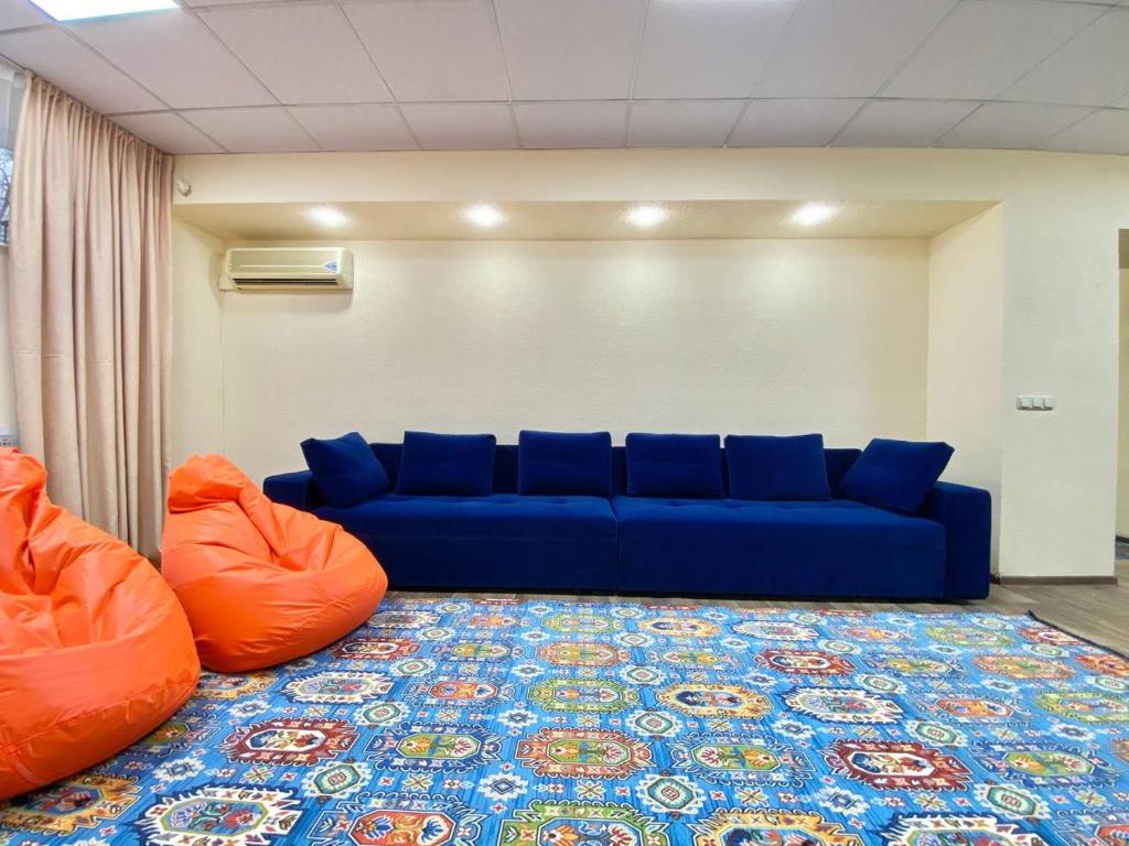 a living room with a blue couch and orange pillows at Alma-Ata Hostel in Almaty
