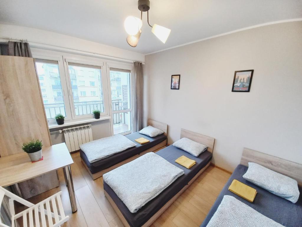 a small room with two beds and a table at Dobre Sny na Konopnej in Bydgoszcz