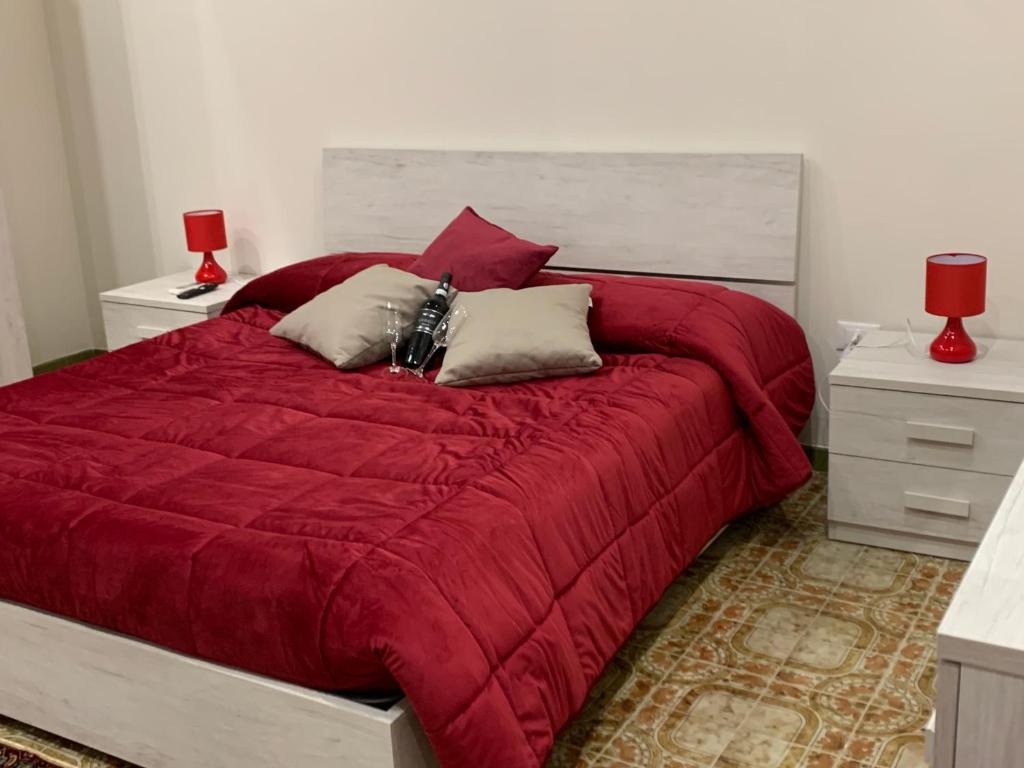 un letto con piumone rosso e due comodini di La Mimosa Case Vacanze a Marsala