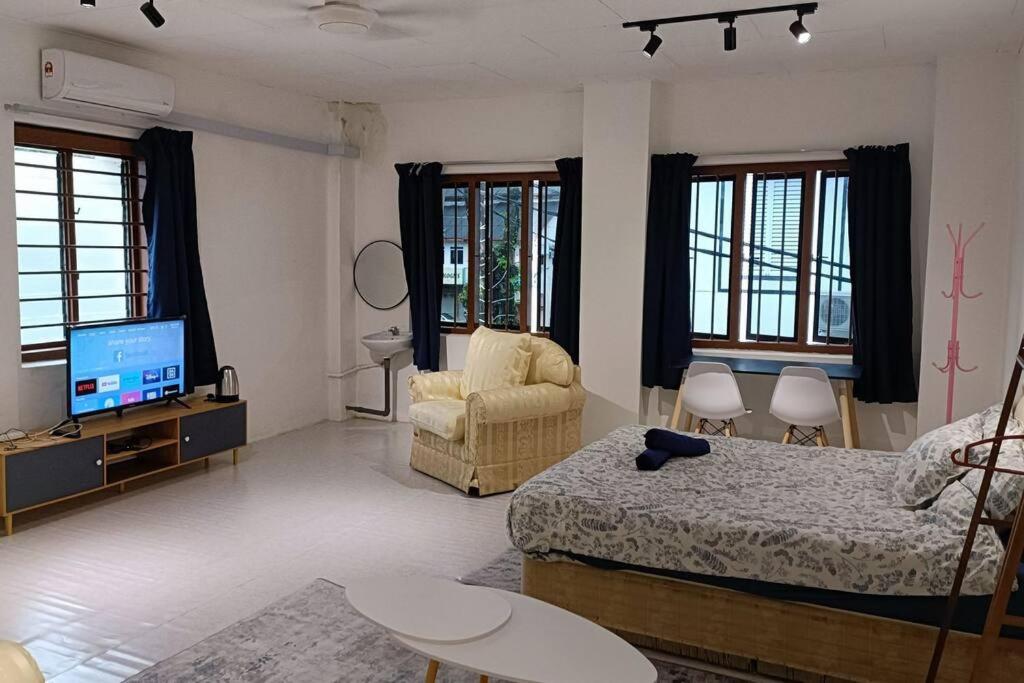 a bedroom with a bed and a couch and a television at 5-Person 1950s Shophouse: Vintage Charm & Smart TVs in Taiping