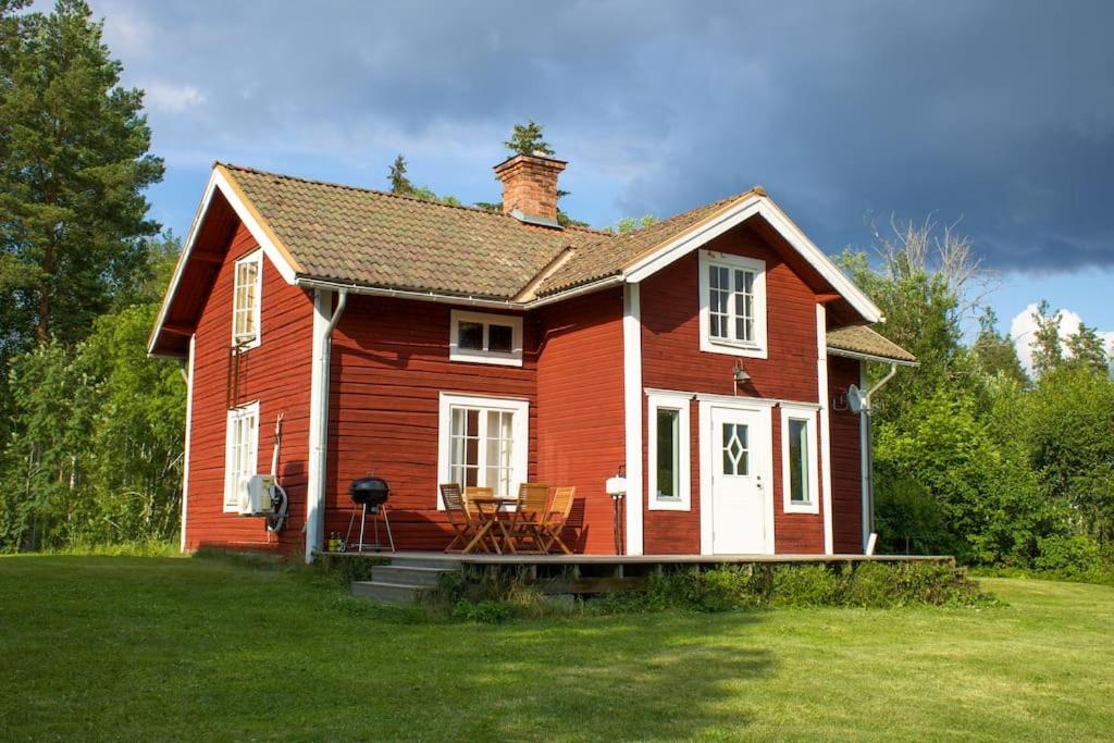 a small red house on a grass field at Scoutstugan in Falun