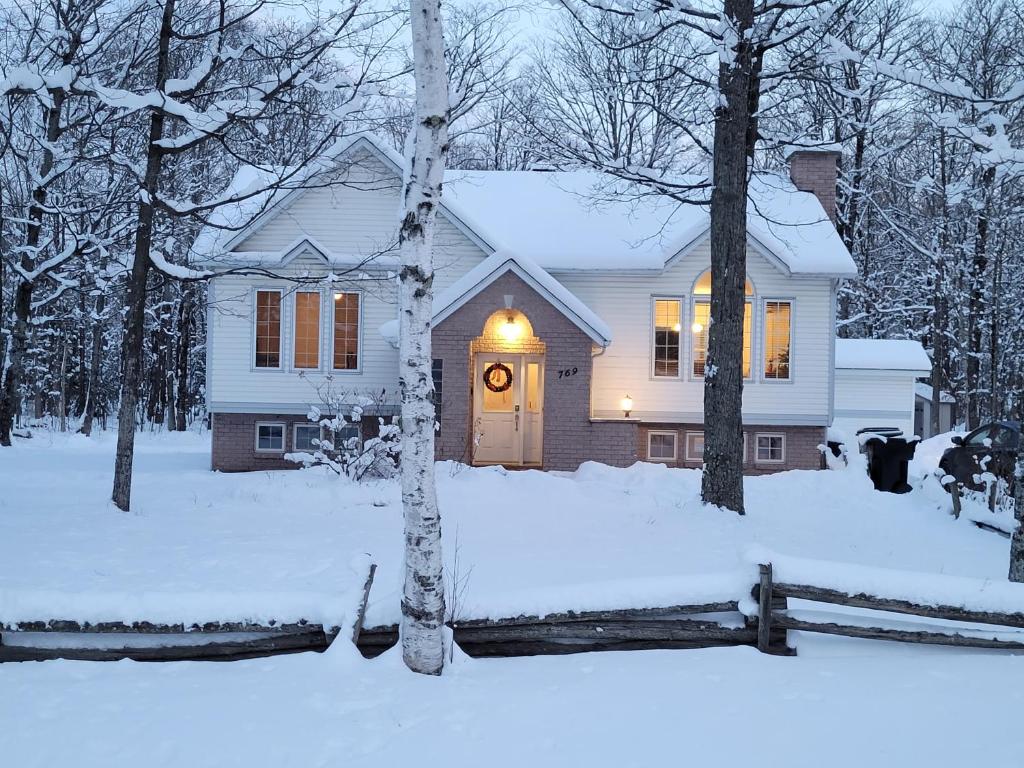 een wit huis met een verlichte deur in de sneeuw bij Le Bethel Quiet and Peaceful Place in Namur