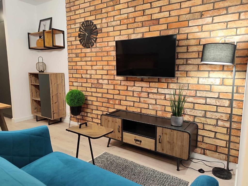 een woonkamer met een bakstenen muur en een flatscreen-tv bij Nova Town Apartament in Stargard
