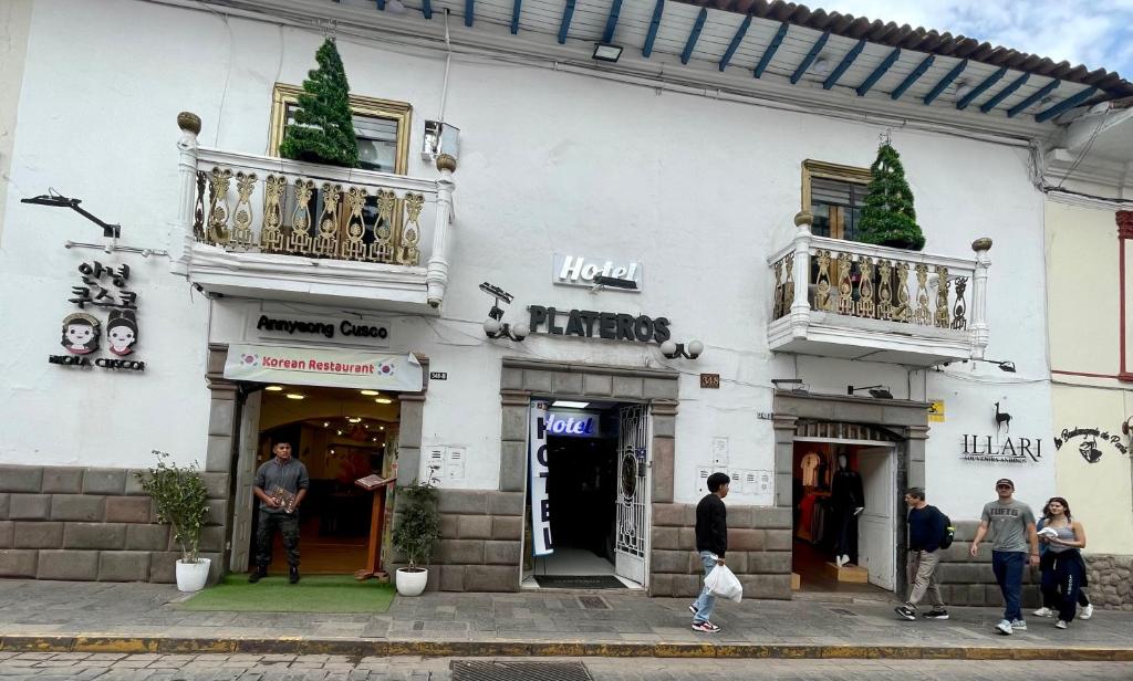 a white building with people standing outside of it at Hotel Plateros in Cusco
