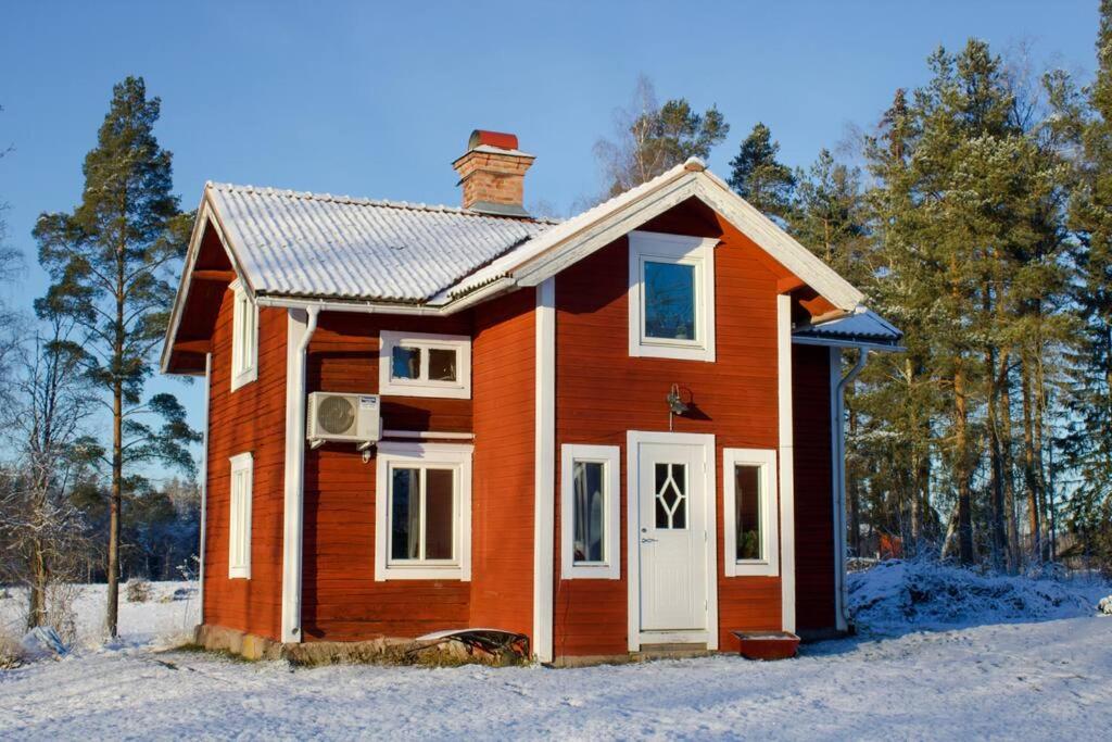 una pequeña casa roja con una puerta blanca en Bagarstugan en Falun