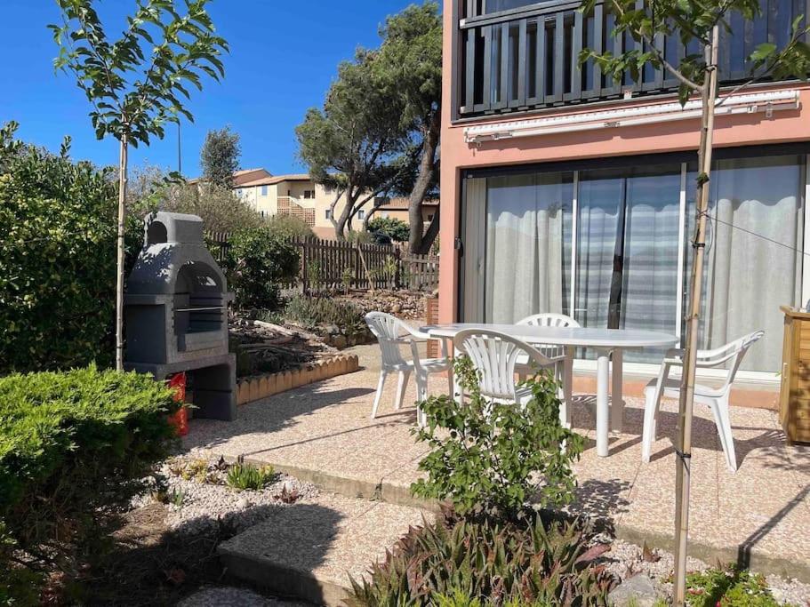 een patio met een tafel en stoelen en een grill bij Logement avec jardin et piscine vue Mer. in Saint Pierre La Mer