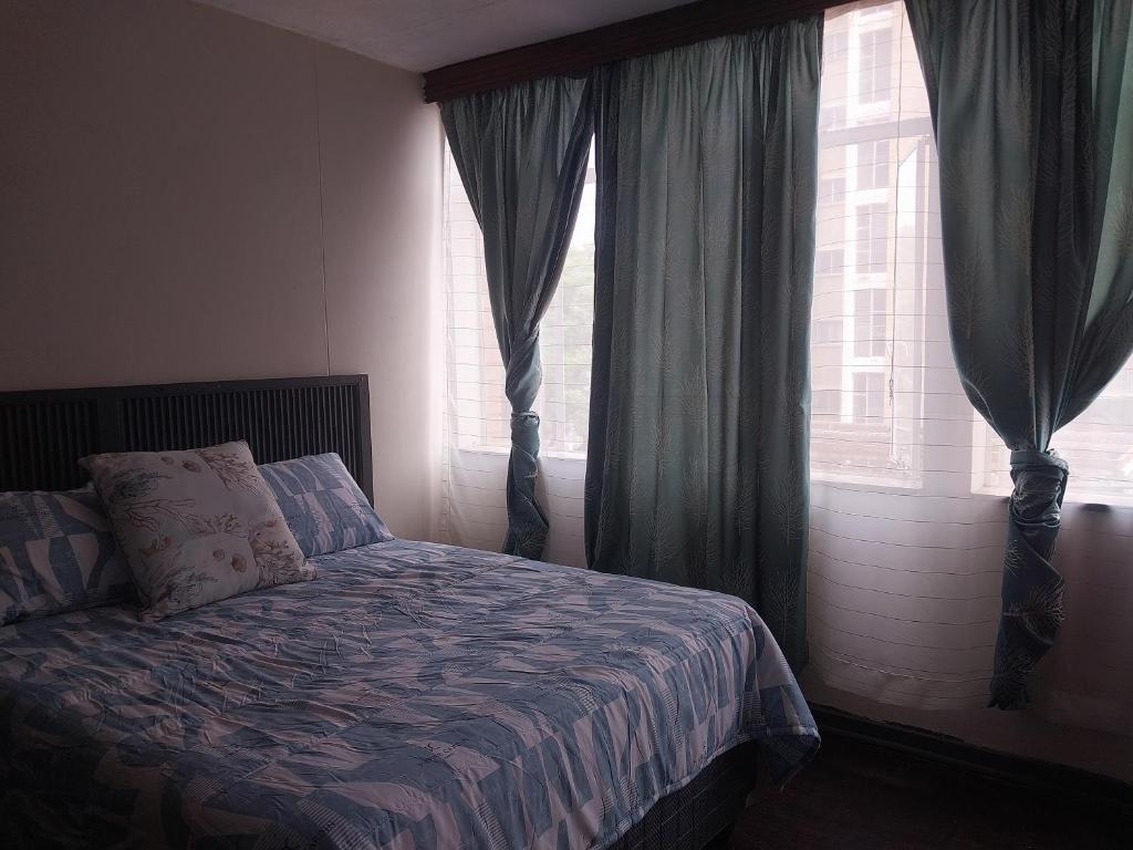 a bedroom with a bed and a window with curtains at Comfy spacious apartment in Pretoria