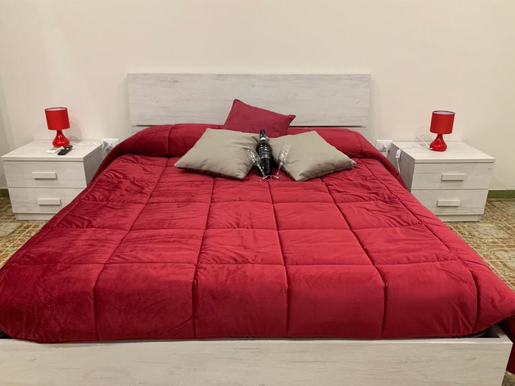 a bedroom with a large red bed with two night stands at La Mimosa Case Vacanze in Marsala