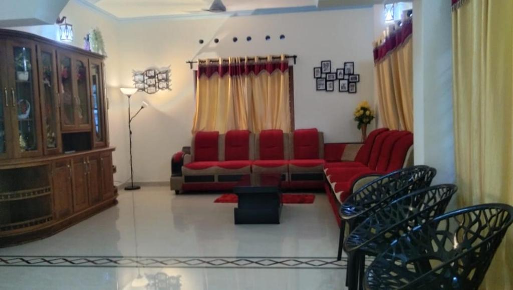 a living room with a red couch and chairs at Greenland Homestay in Manimala