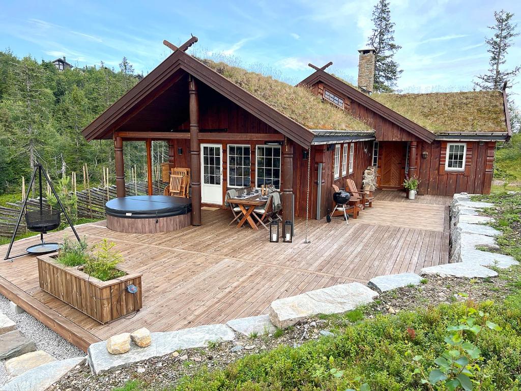 Cette cabine dispose d'une terrasse en bois avec un grill. dans l'établissement Cozy cabin on Lifjell with jacuzzi close to cross-country trails and hiking trails, à Lifjell