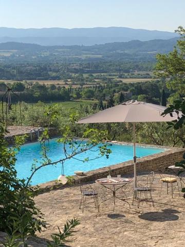 a table and chairs with an umbrella in front of a pool at Les Milles Roches in Gordes