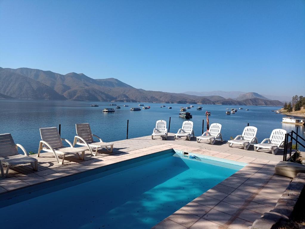 - une piscine avec des chaises et une vue sur le lac dans l'établissement Terrazas Del Lago, à Cabra Corral