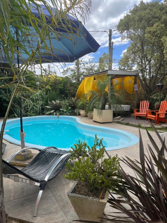 einen Pool mit einem Stuhl und einem Sonnenschirm in der Unterkunft Paz y armonía en Chuy in Chuy