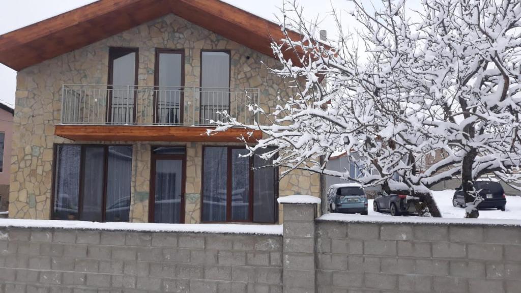 a house with a balcony and a snow covered tree at saxli tyis piras in Bakuriani