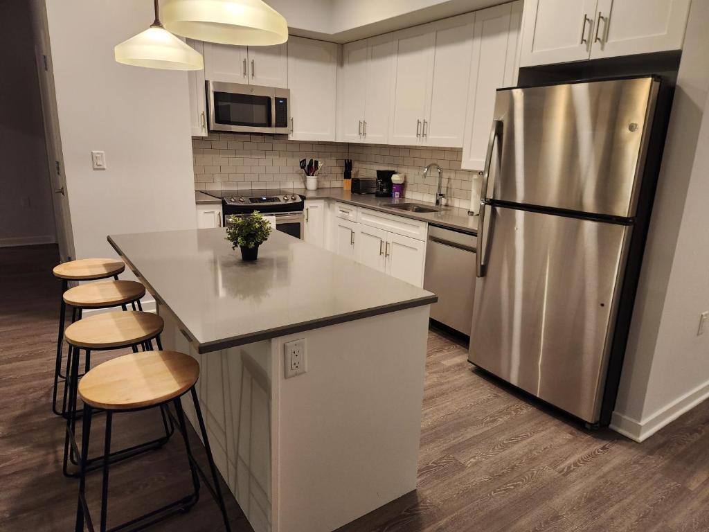 a kitchen with a stainless steel refrigerator and cabinets at Astonishing 2BR Apt Mins to NYC in Jersey City