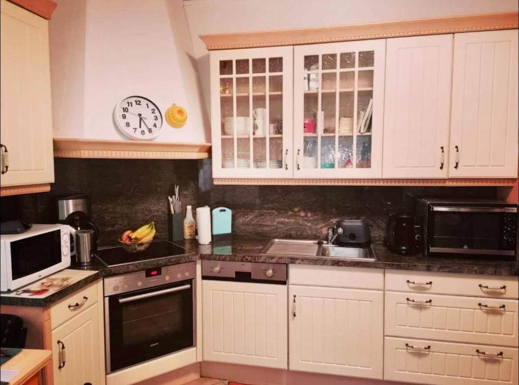 a kitchen with white cabinets and a clock on the wall at Single room for you in Hünxe