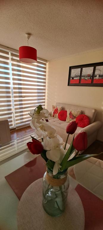 ein Wohnzimmer mit einer Vase mit Blumen auf einem Tisch in der Unterkunft Departamento a pasos del Faro in La Serena