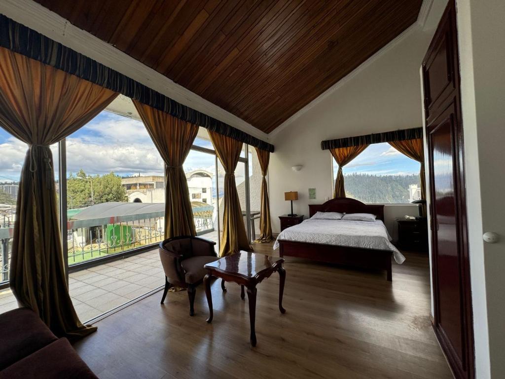 Schlafzimmer mit einem Bett und großen Fenstern in der Unterkunft Suites & Hotel Gonzalez Suarez in Quito