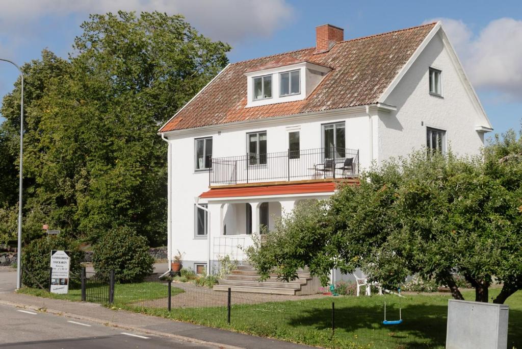 a white house with a balcony on a street at Snickaren Vandrarhem i Grästorp - Egen Lägenhet - Own apartments in Grästorp