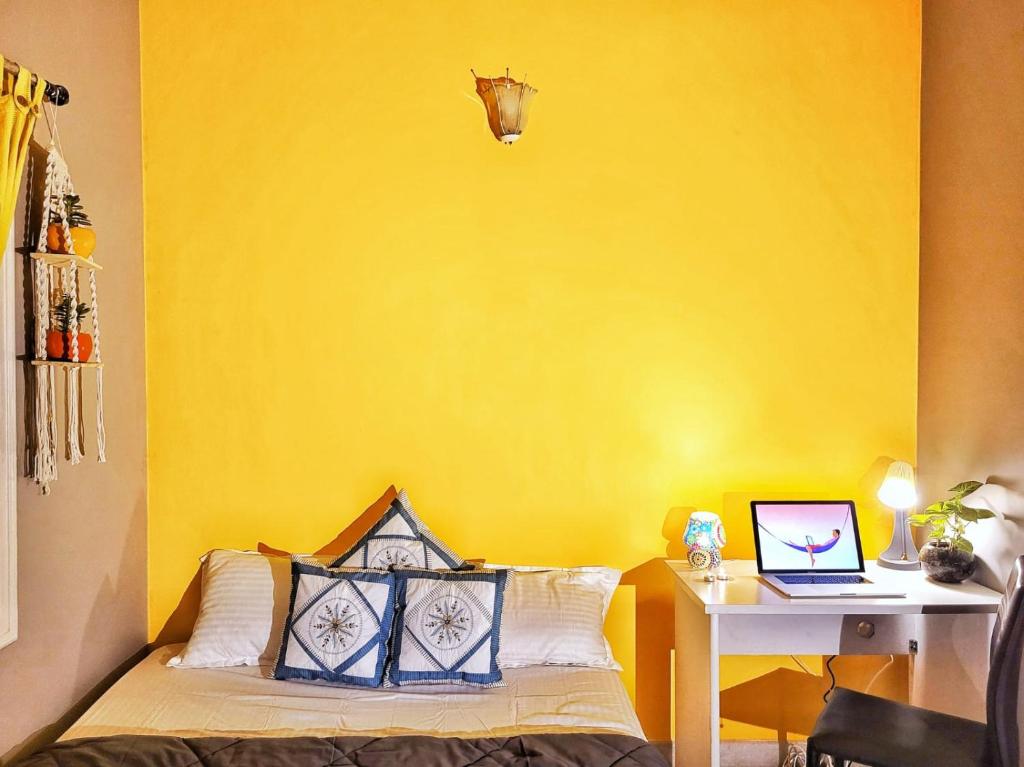 um quarto amarelo com uma cama e uma secretária com um computador portátil em Crimson - Sunflower Skyline em Bangalore