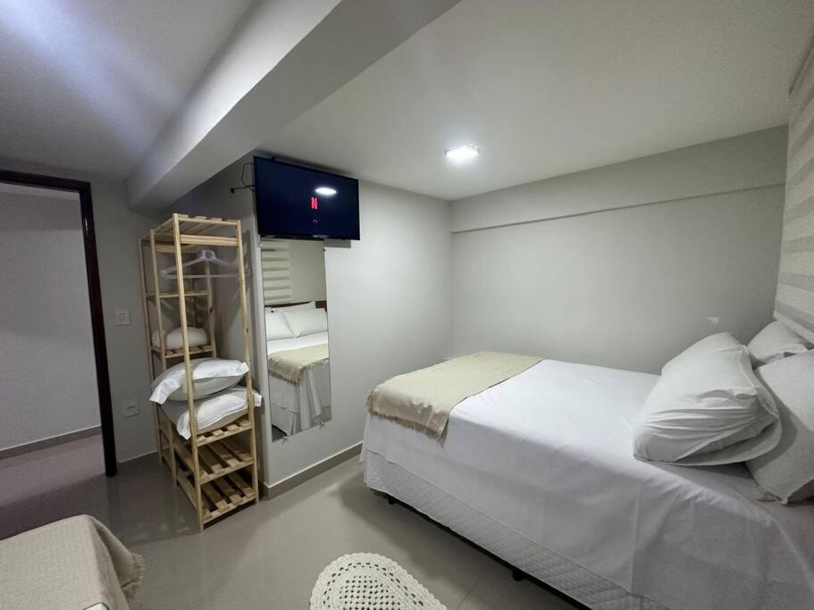 um quarto com uma cama branca e um espelho em Apto 16 lindo e confortável em Montes Claros
