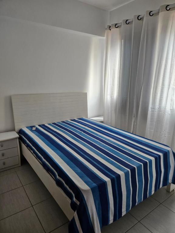 a bedroom with a bed with a blue and white striped blanket at BEACH FLAT in Salvador