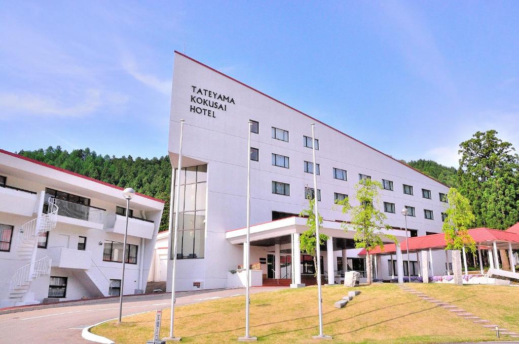 un edificio blanco con un cartel en el costado en Tateyama Kokusai Hotel, en Toyama