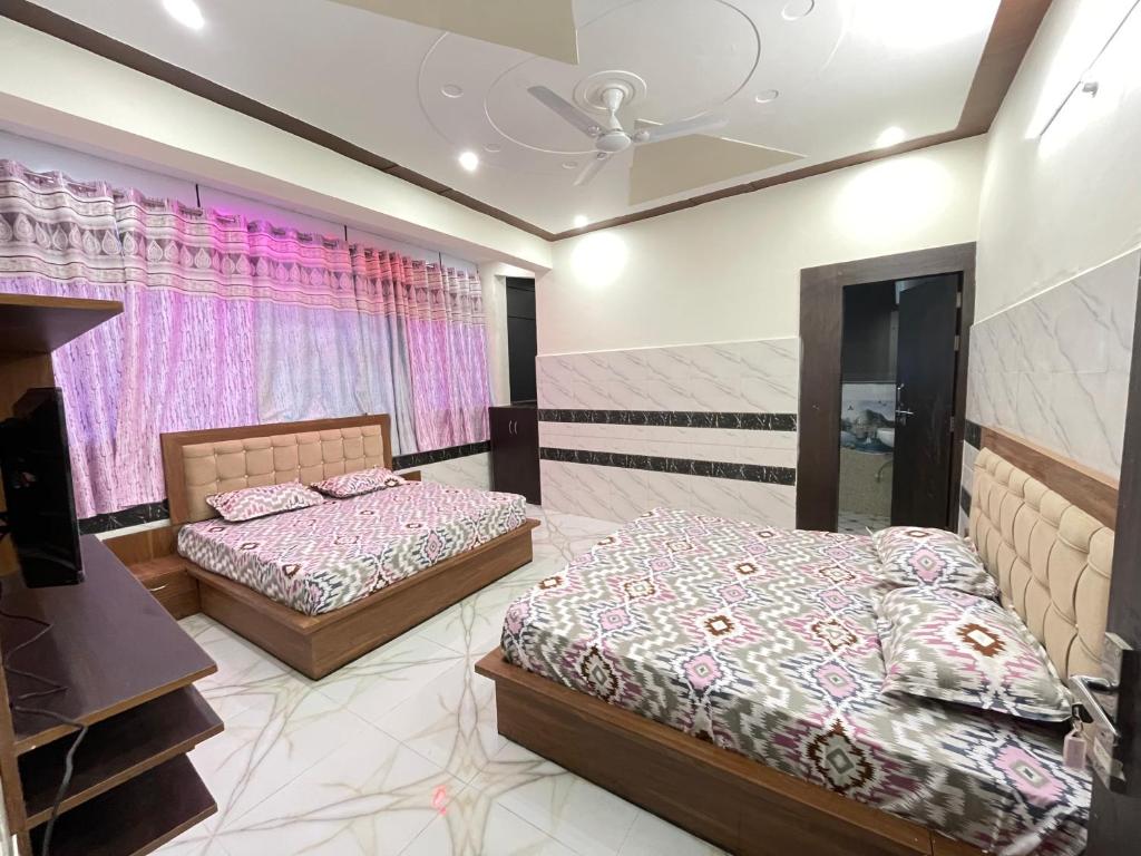 two beds in a bedroom with pink curtains at Gayatri Dham in Vrindāvan