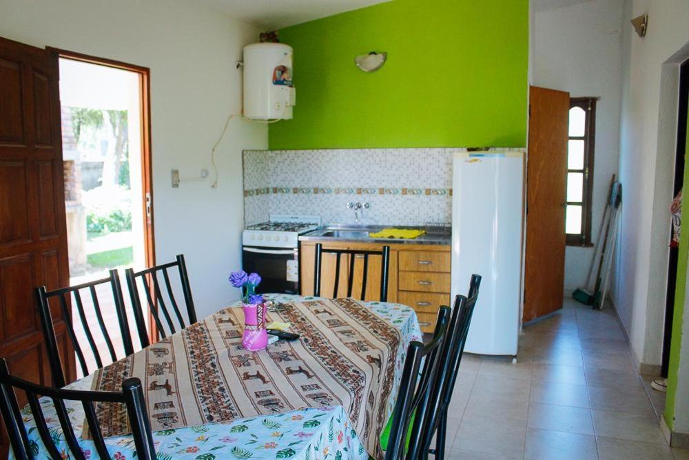 cocina con mesa y pared verde en Cabañas LA ILUSION en La Puerta
