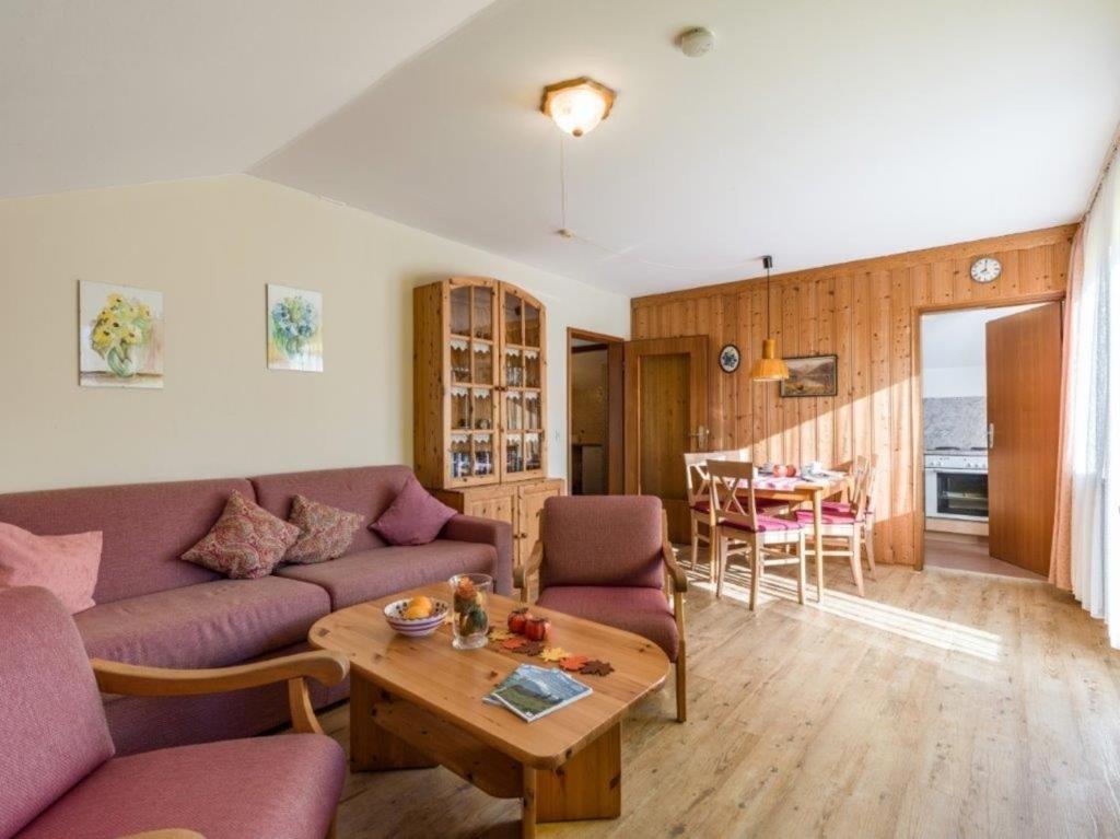 uma sala de estar com um sofá roxo e uma mesa em Chiemgau Comfort A8 Ferienwohnanlage Oberaudorf mit Hallenbad und Sauna em Oberaudorf