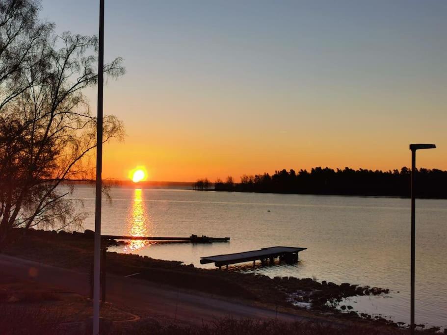 um banco sentado no meio de um lago ao pôr do sol em Gästhus nära havet em Kalmar