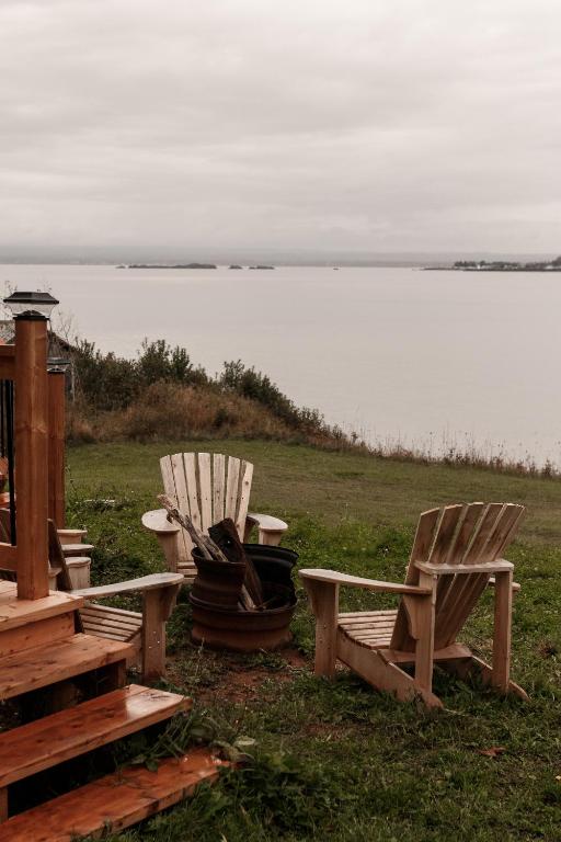 two chairs and a bench next to a body of water at Le Martin Pecheur 2 à 4 personnes in Nouvelle