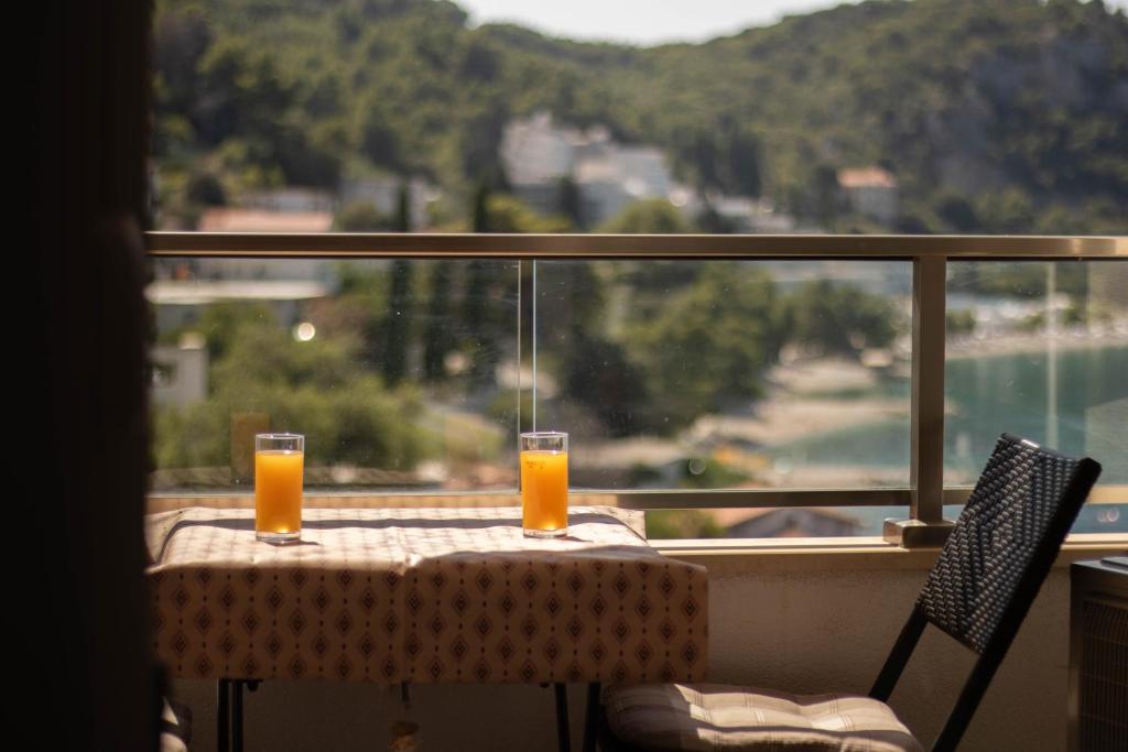 zwei Gläser Orangensaft auf einem Tisch vor einem Fenster in der Unterkunft Apartman Mersab in Živogošće
