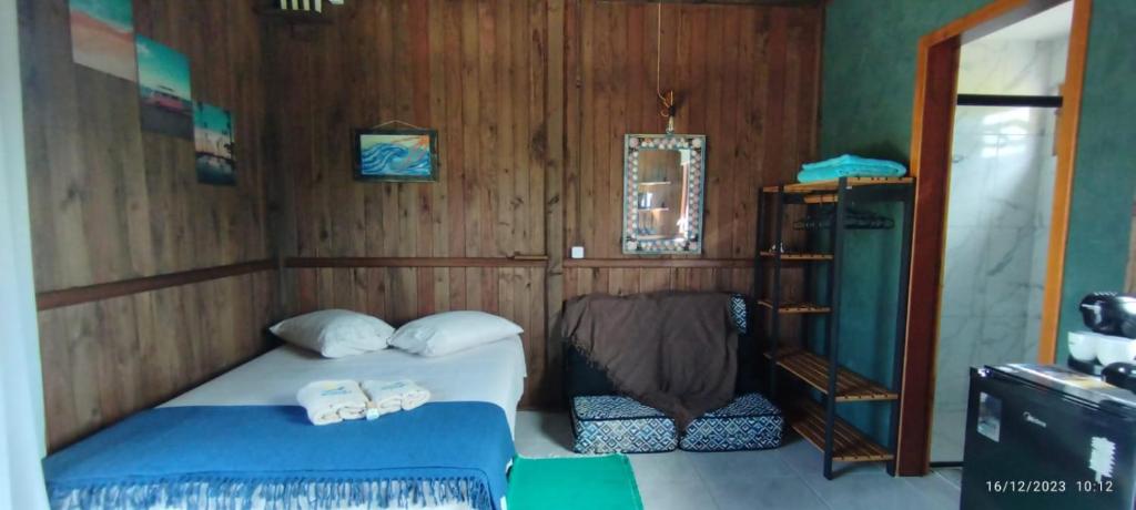 因比圖巴的住宿－Arandu Chalés，一间卧室设有一张床和木墙