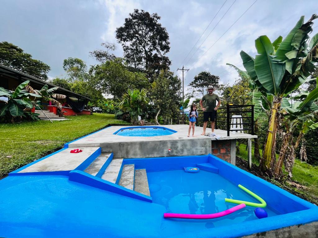 un hombre y un niño parados junto a dos piscinas en Yellow House en Quimbaya
