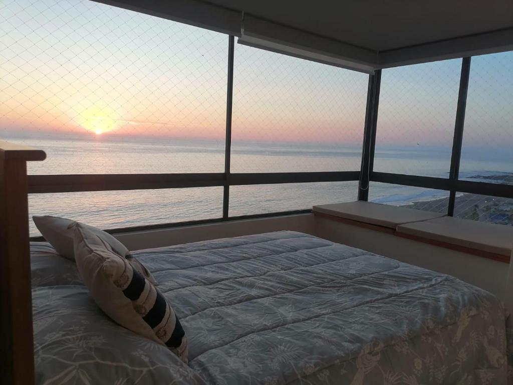 Cama en habitación con vistas al océano en departamento frente al mar playa brava, en Iquique