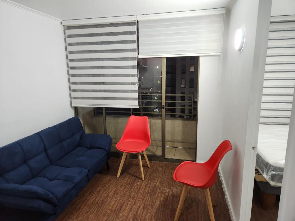 a living room with a blue couch and two red chairs at Vivaceta Metro Hospitales in Santiago