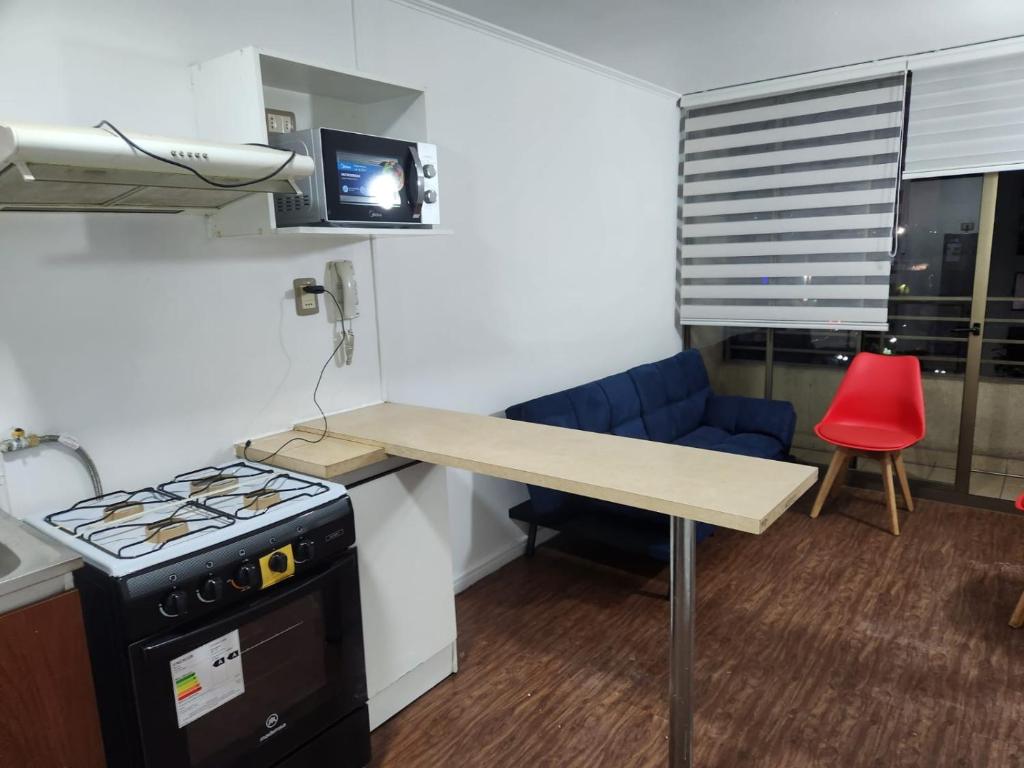 a kitchen with a stove and a table and a red chair at Vivaceta Metro Hospitales in Santiago