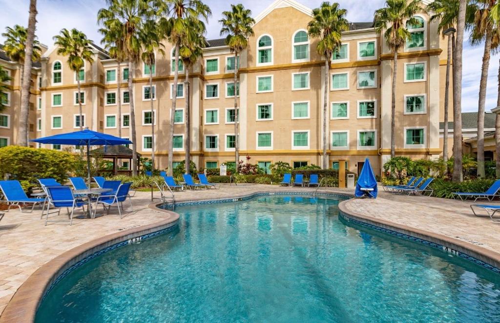 un hotel con una piscina con sillas y un edificio en Family Condo-2 rooms Top floor pool view -Theme parks Free Shuttle en Orlando