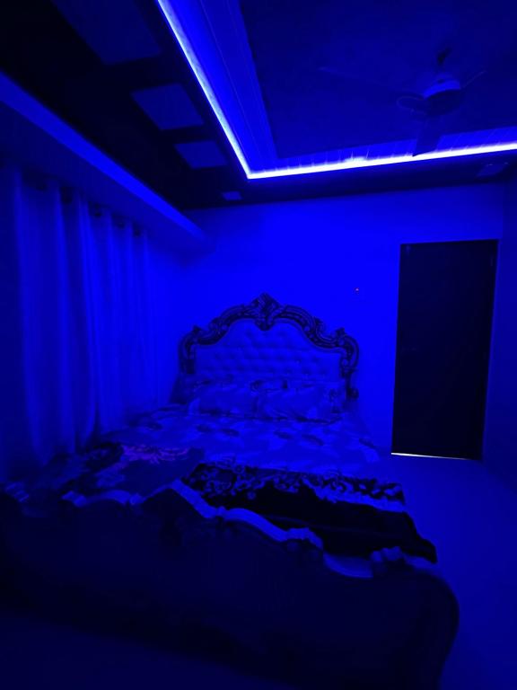 a dark room with a bed in a blue room at Janhavi Villa in Dapoli