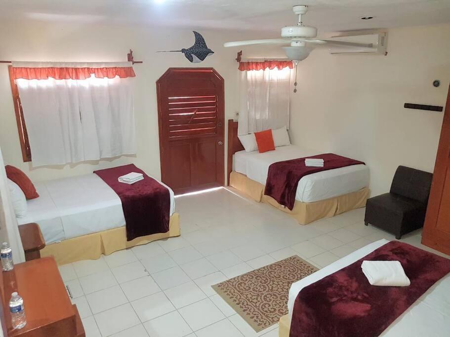 a hotel room with two beds and a chair at Hotel Fisherman lodge, cuarto base triple in Punta Allen