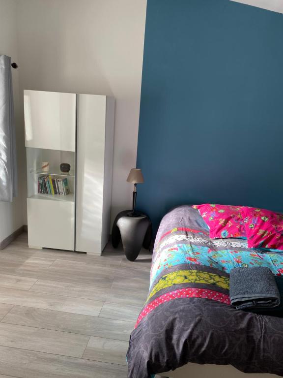 une chambre avec un lit et un mur bleu dans l'établissement Gîte mitoyen gorges de la Monne - Olloix, à Olloix