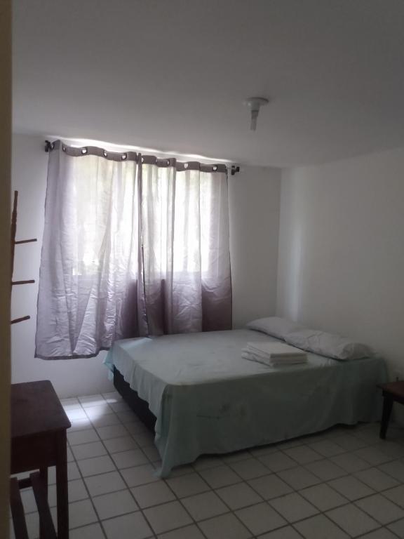 1 dormitorio con 1 cama y una ventana con cortinas blancas en Quarto Casal privativo em apartamento, en Salvador