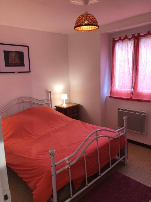 een slaapkamer met een bed met een rood dekbed bij L’occitanine in Capdenac-Gare