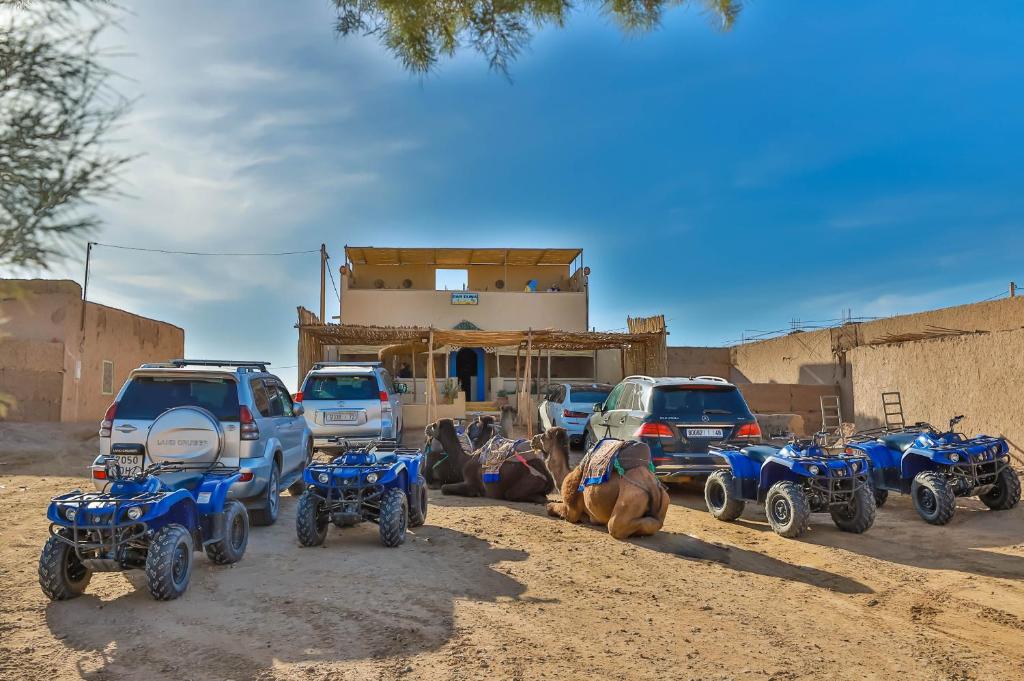 a group of motorcycles and cars parked in the dirt at Dar Duna in Hassilabied